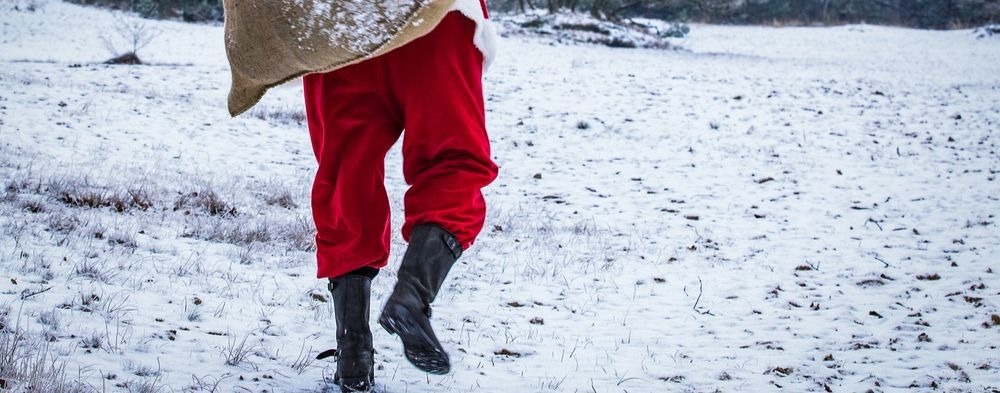 Santa figure carrying a sack and waling through the snow