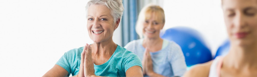 Smiling woman with hands in prayer in yoga class