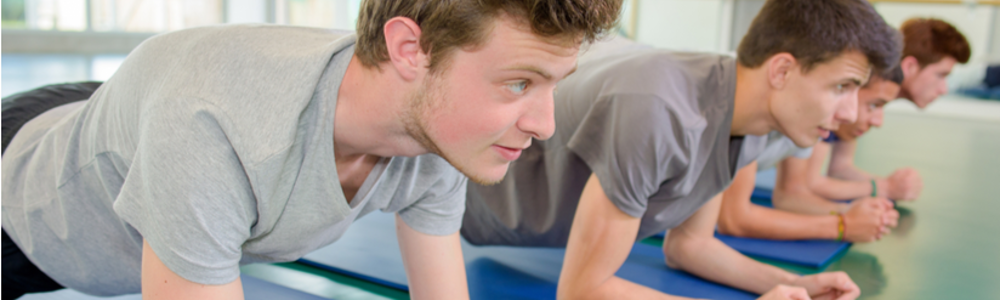 Older teenage boys holding the plank position in an exercise studio