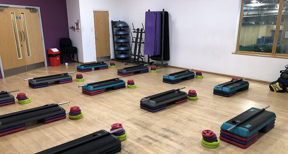 Exercise studio with step, bar and weights laid out ready for a class