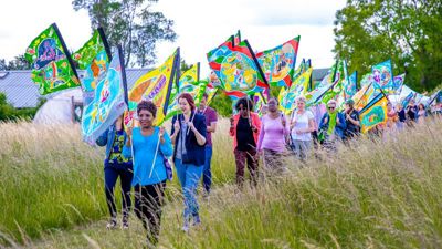 People carrying the colourful C100 flags through a field. 