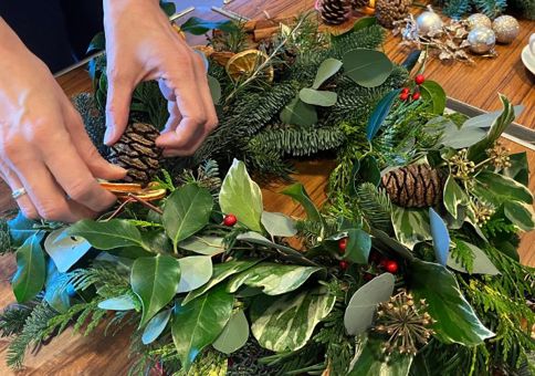 Person making wreath from evergreen foilage