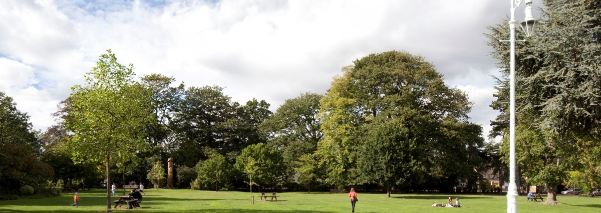 Green space with trees and benches and people walking