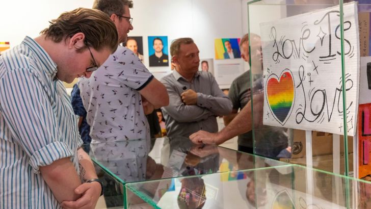 A person looking into a display cabinet at the Behind the Rainbow exhibition launch.