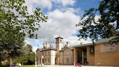 The exterior of Chelmsford Museum with visitors playing on the front lawn. 