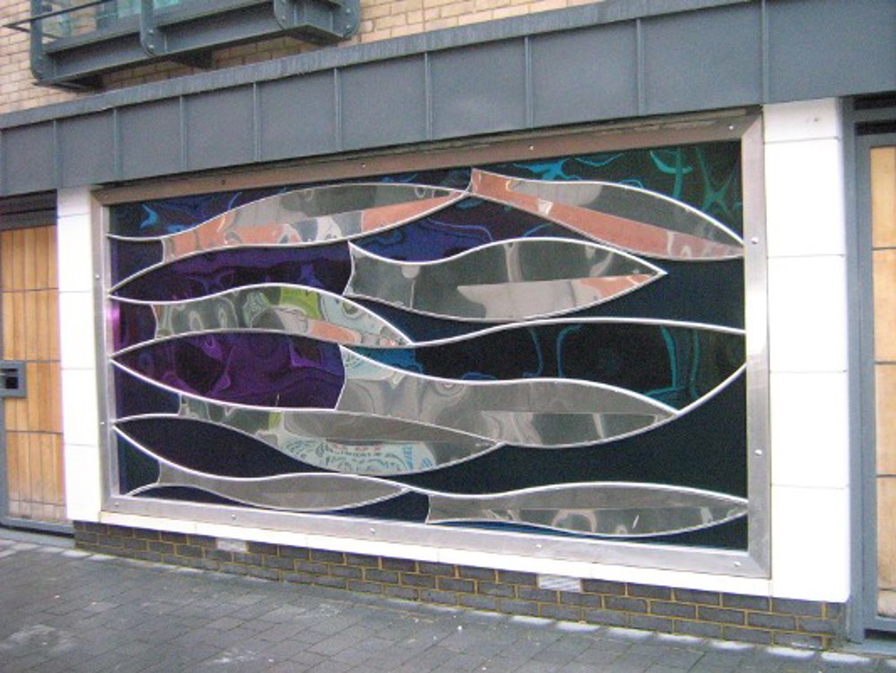 Steel sculpture of fish on the side of a building