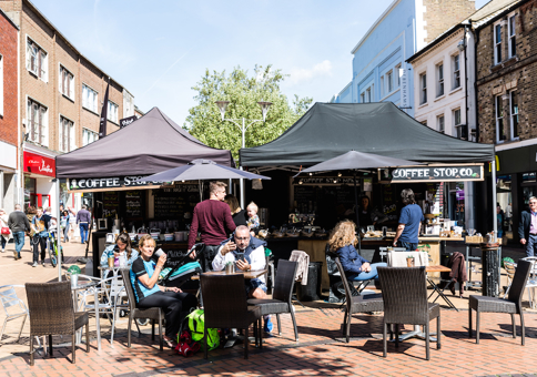 People sitting at tables by coffee stall in High Street