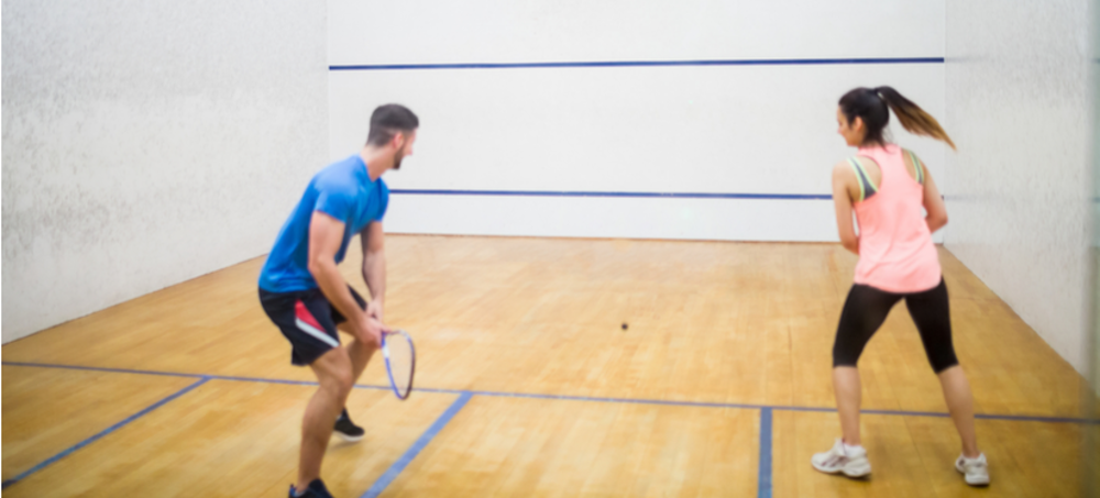 Man and woman playing on squash court