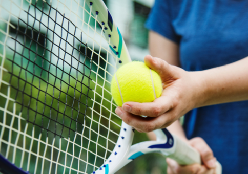 Person holding tennis racket and yellow tennis ball