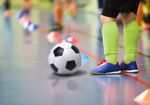 Young footballer's feet on a sports hall waiting to shoot a football