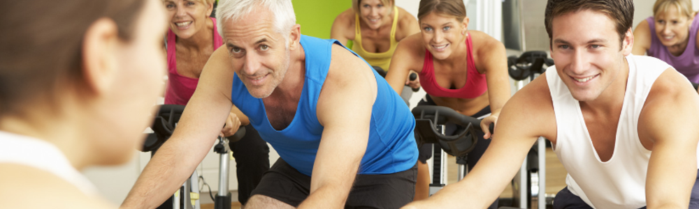 A group of adults participate in a cycling exercise class