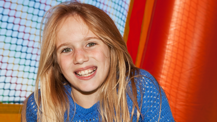 Smiling girl sitting inside colourful bouncy castle