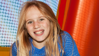 Smiling girl sitting inside colourful bouncy castle preview