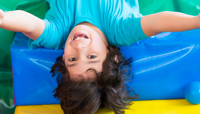Smiling boy laying on colourful soft play cushions preview