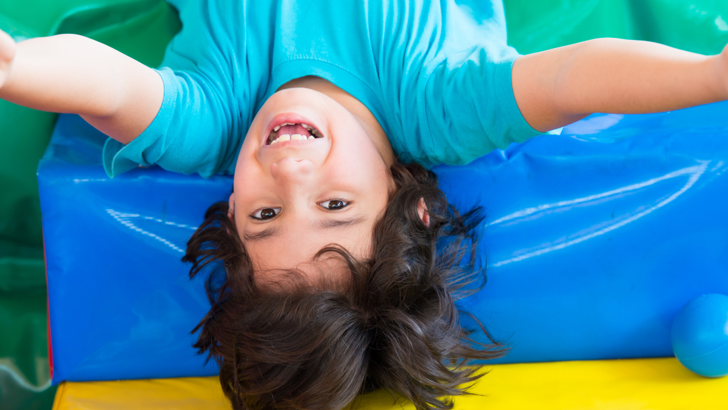 Smiling boy laying on colourful soft play cushions