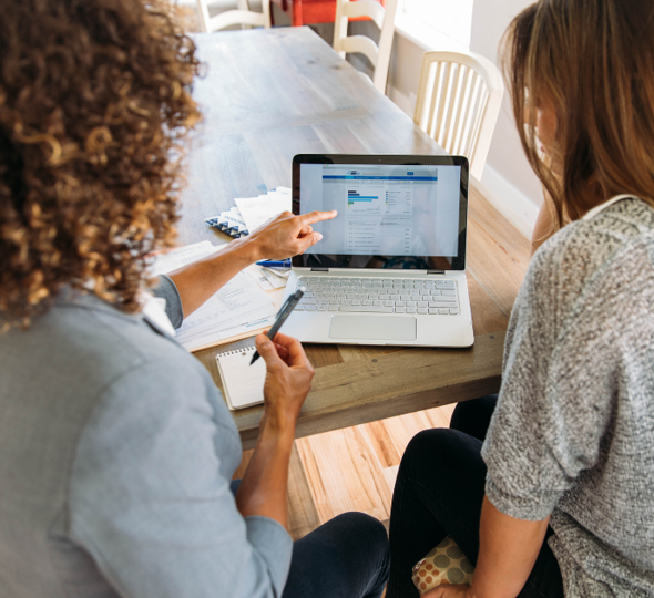 Two women both looking at a laptop