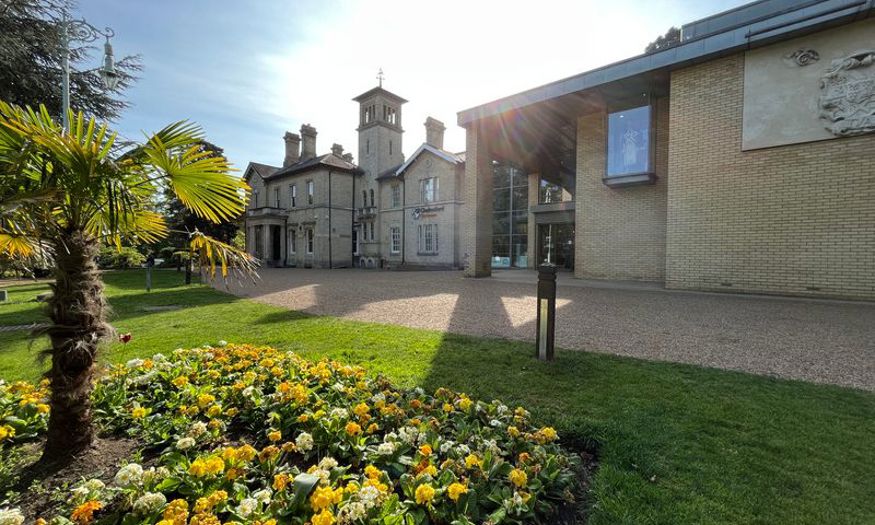 Outside Chelmsford Museum on a sunny day with a patch of flowers in the foreground. 