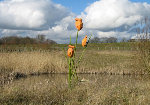 Sculpture of large orange bugs climbing on green stems