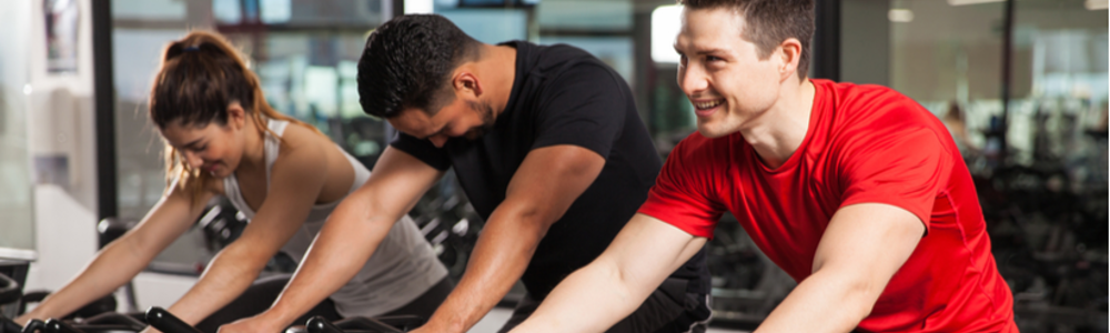 Three people take a group cycling class