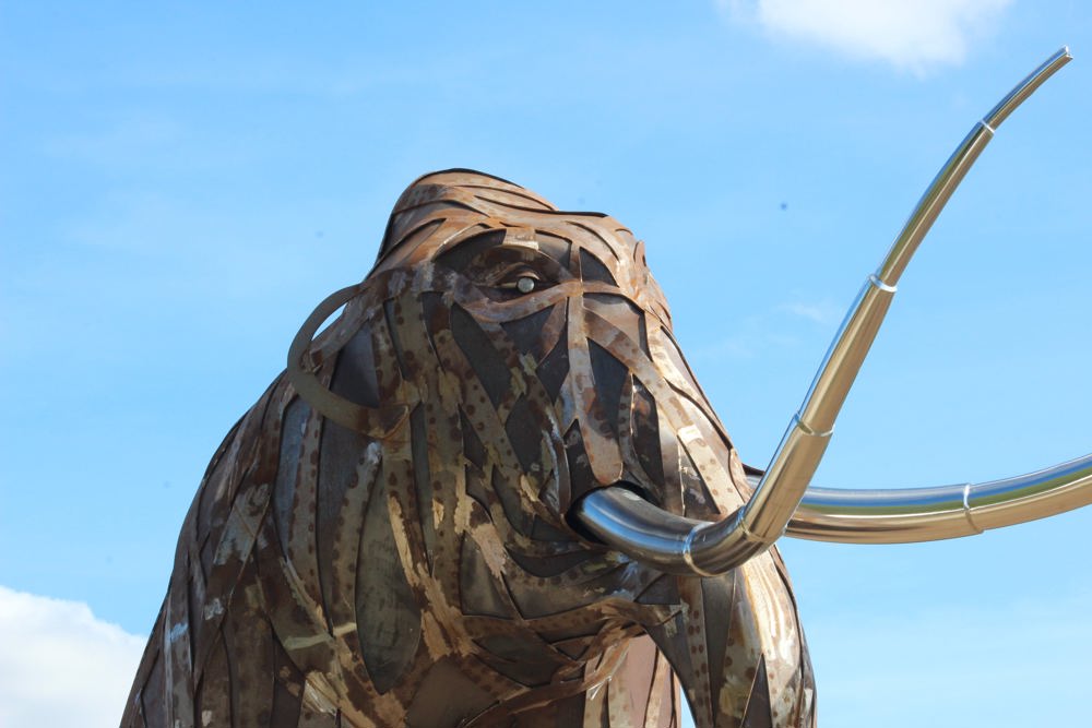 Large metal mammoth sculpture with metalwork skin comprising of a stream of overlapping strips