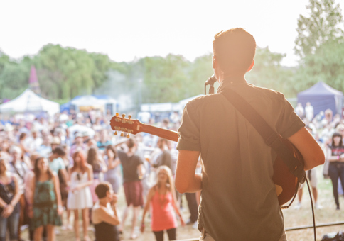 Man singing and playing guitar on stage, looking out at audience