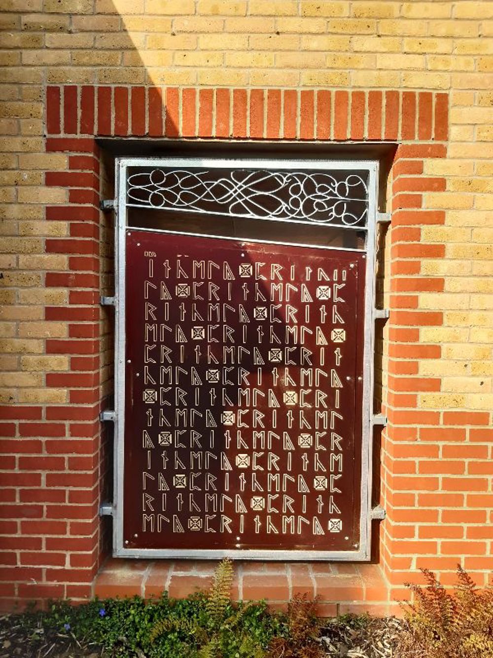 Large panel recessed into brick wall and covered with runes